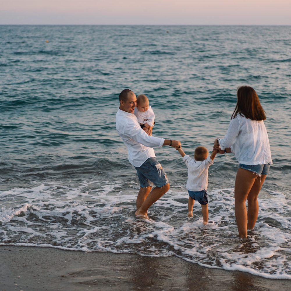 Happy family having fun playing beach in summer vacation on the beach. Happy family and vacations concept. Seascape at sunset with beautiful sky. Family on the beach.